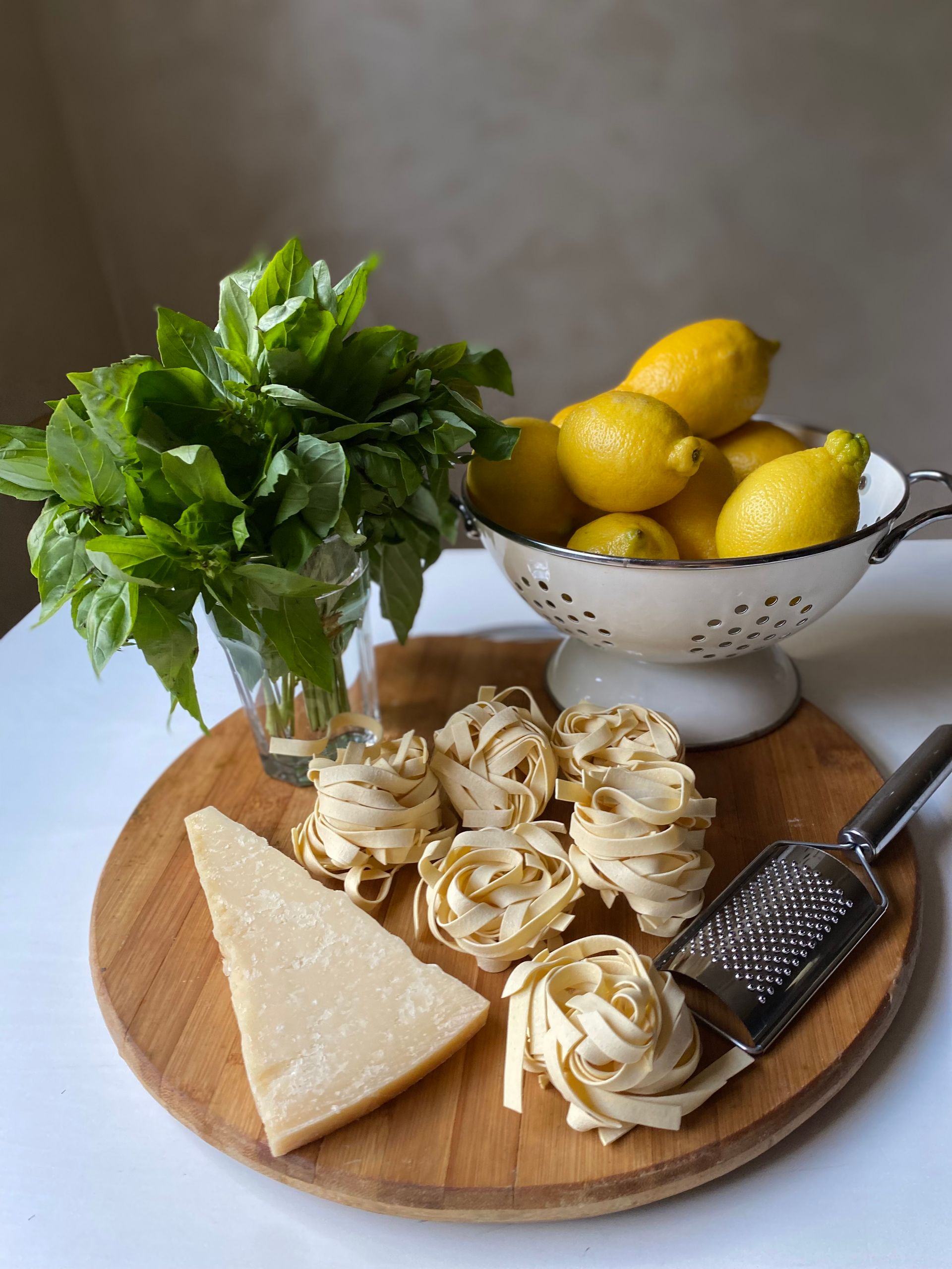Rustic setup with pasta, lemons, parmesan, and basil ready for a traditional Italian dish.